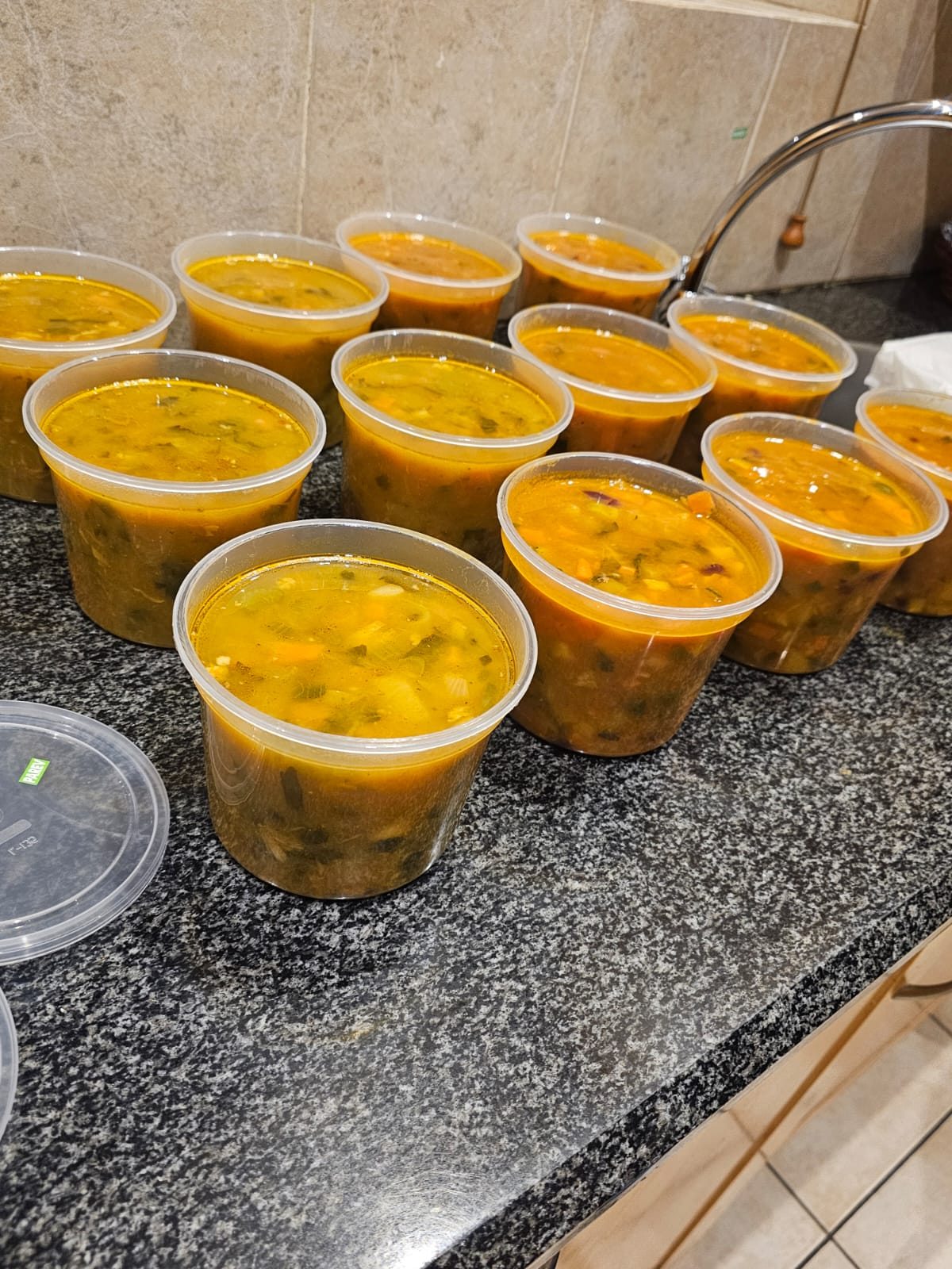 Close view of hearty vegetable soup portioned into takeaway containers