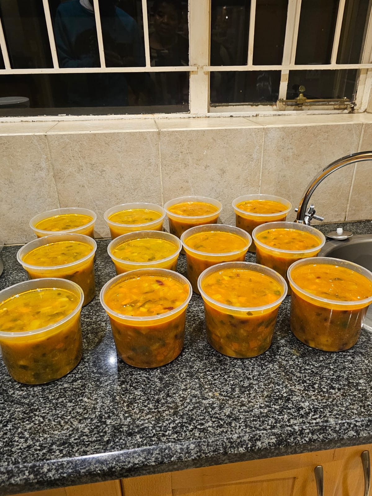 Containers of freshly cooked hearty soup cooling in the kitchen